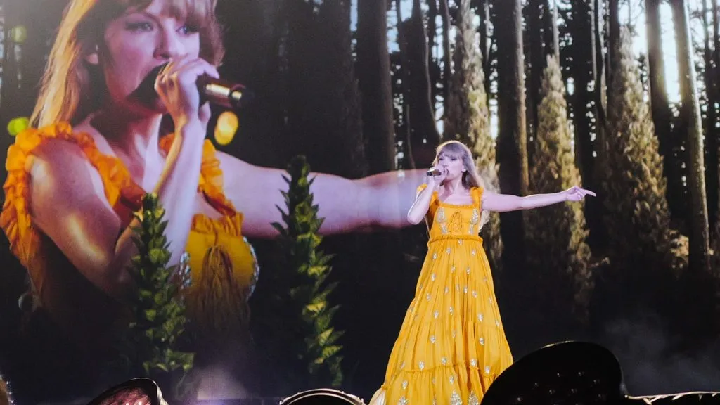 Taylor Swift in abito giallo si esibisce sul palco durante il suo Eras Tour